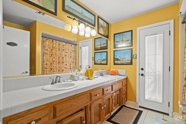 bathroom featuring double vanity, visible vents, a sink, and tile patterned floors