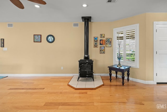 interior details with visible vents, wood finished floors, a wood stove, and recessed lighting