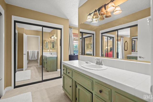 ensuite bathroom with ensuite bath, two vanities, and a sink