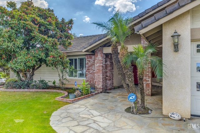 property entrance featuring a tiled roof, brick siding, and a lawn