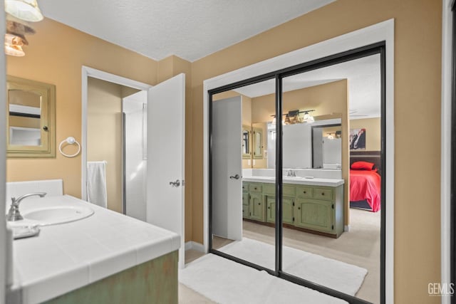 ensuite bathroom with baseboards, ensuite bath, vanity, and a textured ceiling