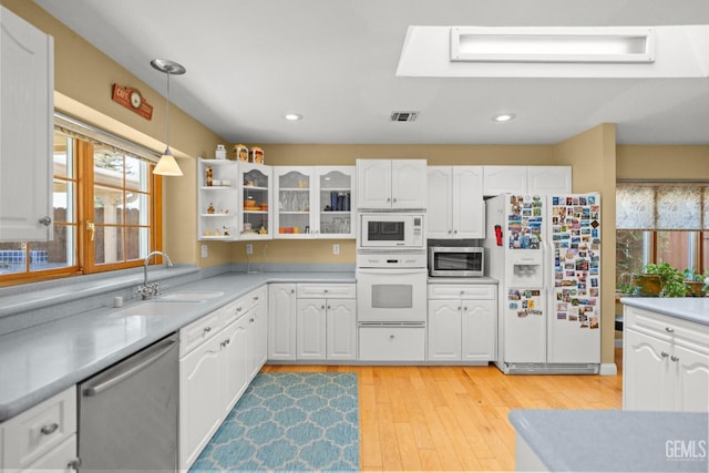 kitchen with visible vents, decorative light fixtures, stainless steel appliances, white cabinetry, and a sink