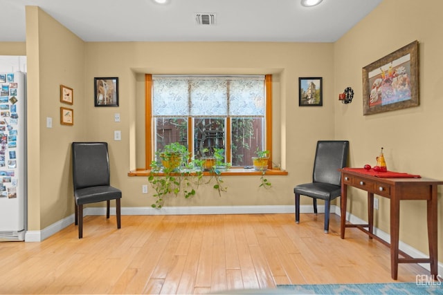 sitting room with wood finished floors, visible vents, and baseboards