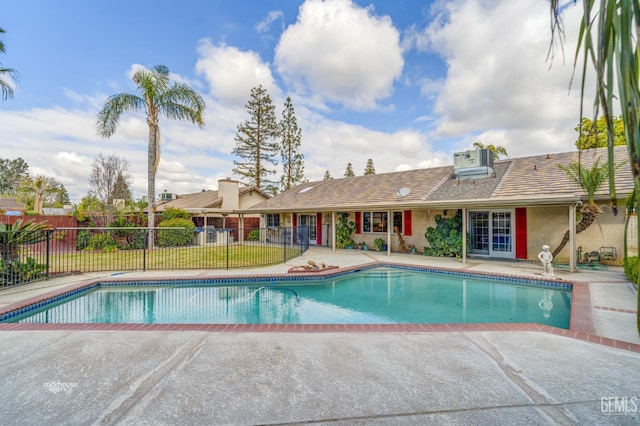 view of pool featuring central AC, fence, french doors, a fenced in pool, and a patio area