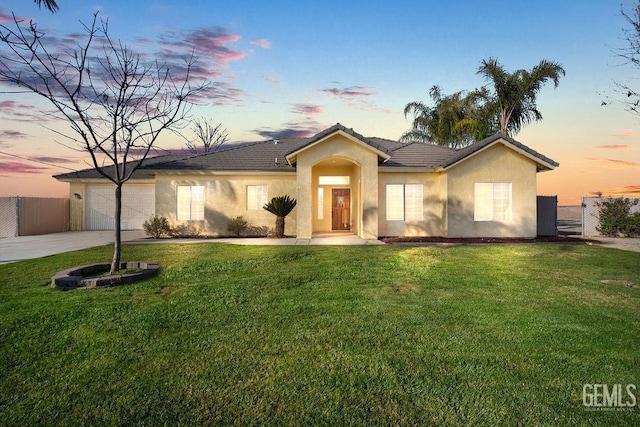 single story home featuring a garage and a lawn