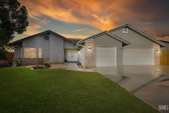 ranch-style house with a garage and a lawn