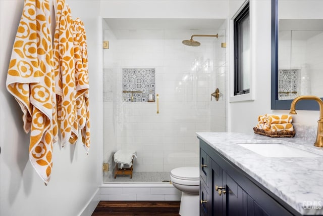 bathroom featuring wood-type flooring, toilet, a shower with door, and vanity