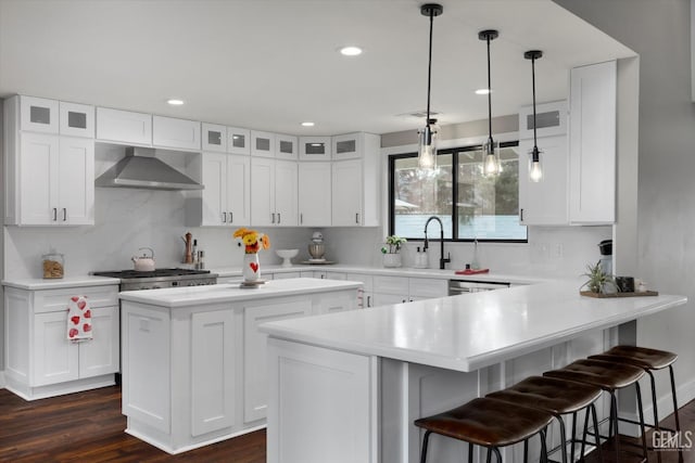 kitchen with a kitchen island, kitchen peninsula, white cabinets, and wall chimney exhaust hood