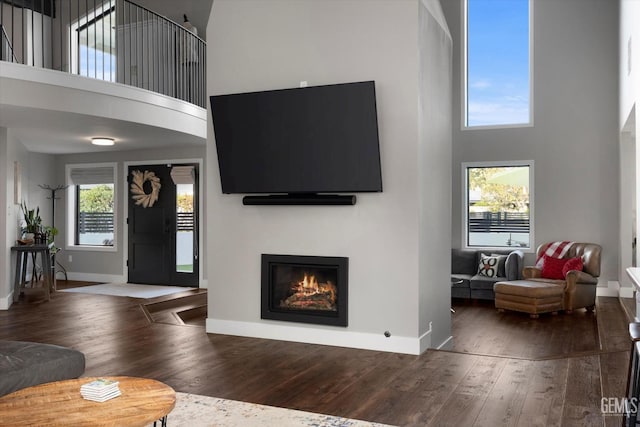 living room with a towering ceiling and dark hardwood / wood-style flooring