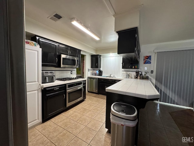6301 Scenic Way, Bakersfield, CA 93309 - kitchen with stainless steel appliances, dark cabinetry, tile counters, a sink, and a peninsula