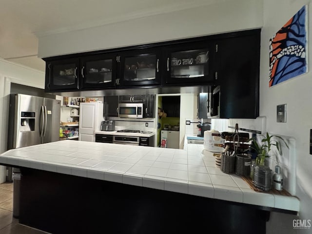 6301 Scenic Way, Bakersfield, CA 93309 - kitchen featuring dark cabinetry, ornamental molding, glass insert cabinets, appliances with stainless steel finishes, and backsplash