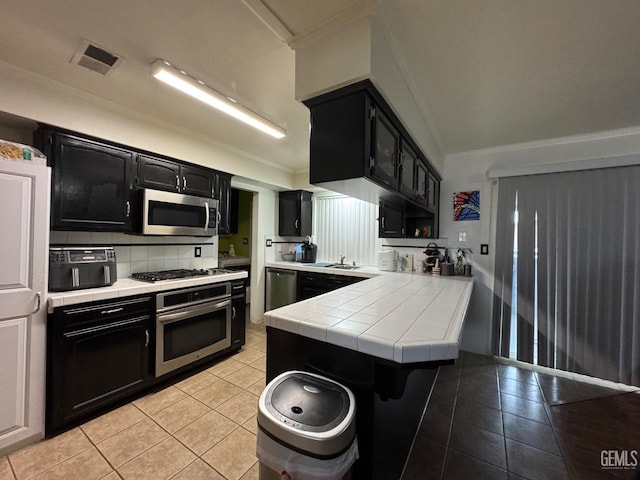 6301 Scenic Way, Bakersfield, CA 93309 - kitchen with dark cabinets, stainless steel appliances, tile countertops, crown molding, and light tile patterned floors