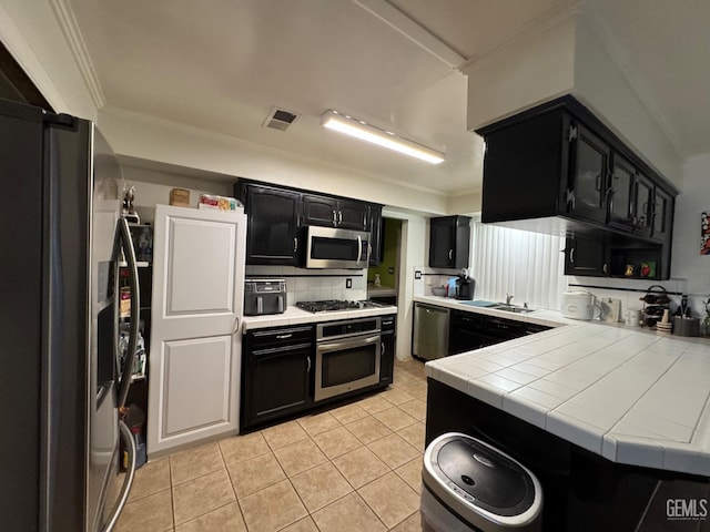 6301 Scenic Way, Bakersfield, CA 93309 - kitchen with dark cabinets, stainless steel appliances, light tile patterned floors, ornamental molding, and tile counters