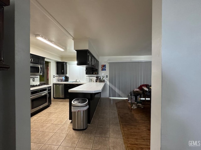 6301 Scenic Way, Bakersfield, CA 93309 - kitchen featuring stainless steel appliances, tile countertops, dark cabinets, light tile patterned floors, and a peninsula