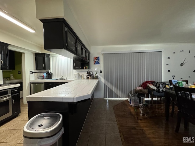 6301 Scenic Way, Bakersfield, CA 93309 - kitchen featuring dark cabinets, light tile patterned floors, appliances with stainless steel finishes, and tile countertops