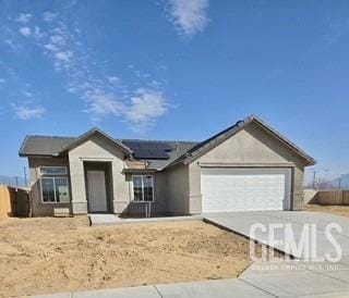 view of front of home featuring driveway, an attached garage, and roof mounted solar panels