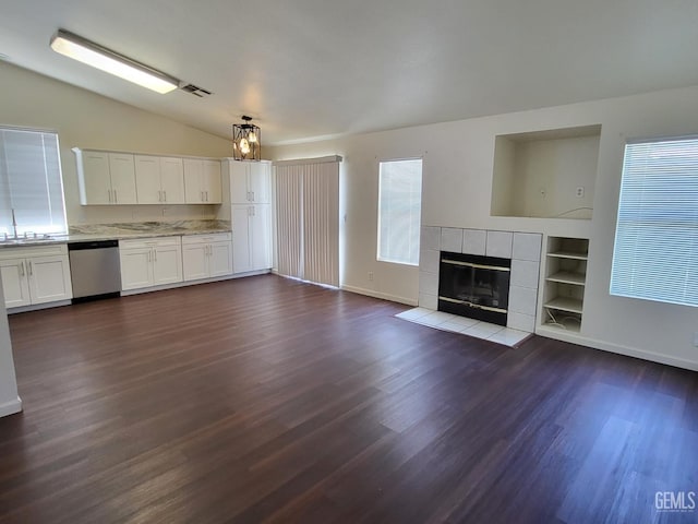 11511 Bay Meadows Ln, Bakersfield, CA 93312 - unfurnished living room featuring vaulted ceiling, dark wood-style flooring, a tiled fireplace, and built in features
