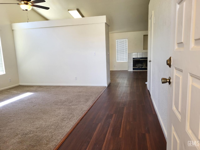 11511 Bay Meadows Ln, Bakersfield, CA 93312 - empty room with ceiling fan, a tiled fireplace, dark wood-type flooring, and vaulted ceiling