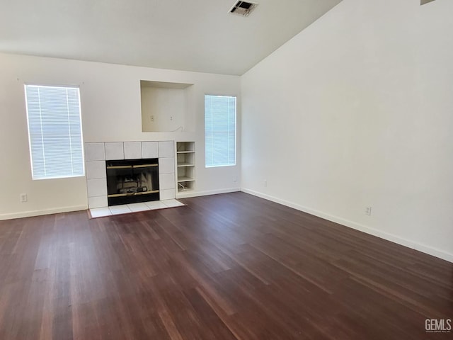 11511 Bay Meadows Ln, Bakersfield, CA 93312 - unfurnished living room with vaulted ceiling, dark wood-type flooring, built in shelves, and a tile fireplace