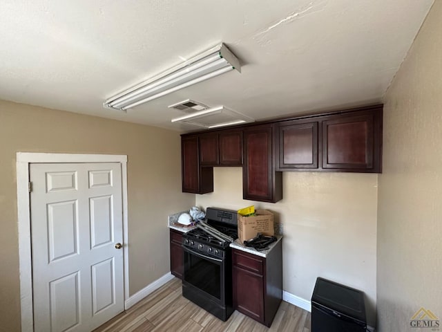 kitchen featuring visible vents, baseboards, light wood-style floors, dark brown cabinets, and black range with gas stovetop