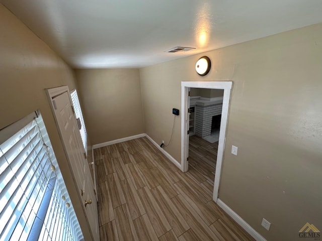 corridor with wood finish floors, visible vents, and baseboards