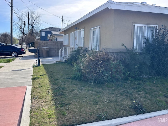 view of property exterior featuring a yard, fence, and stucco siding