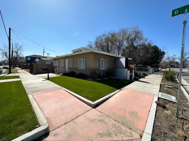 view of side of home with stucco siding, fence, and a yard