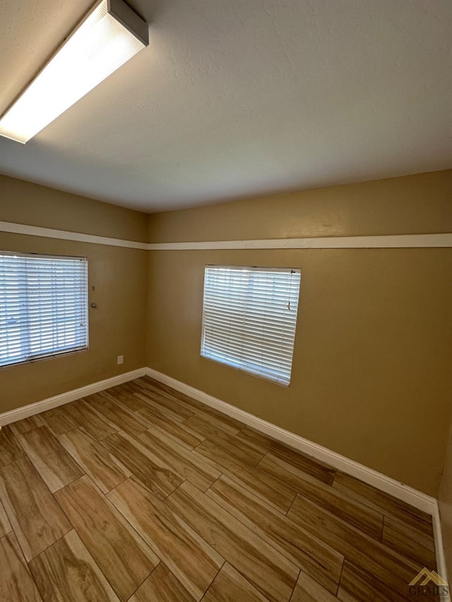 unfurnished room with baseboards and wood finished floors