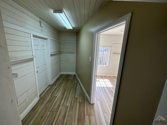 hallway featuring wooden ceiling, baseboards, and wood finished floors