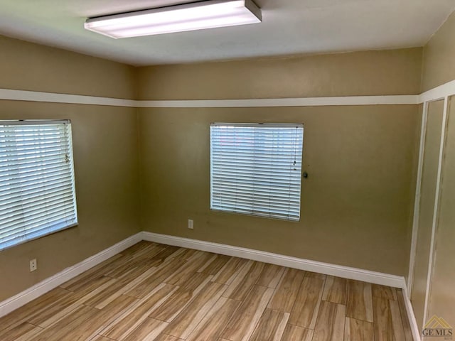 unfurnished room with light wood-style flooring and baseboards