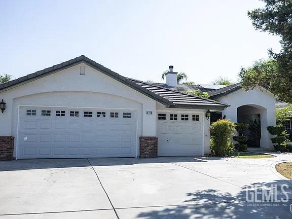 view of front of house featuring concrete driveway, a chimney, an attached garage, and stucco siding