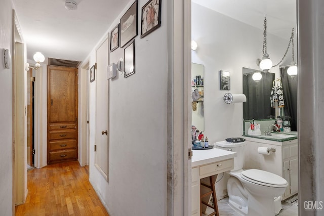 bathroom featuring toilet, wood finished floors, and vanity