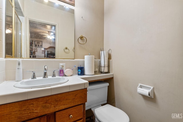 bathroom with vanity, toilet, and decorative backsplash