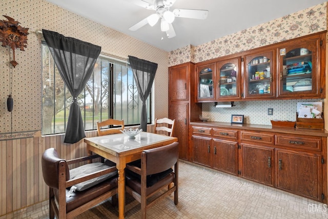 dining space featuring a ceiling fan and wallpapered walls