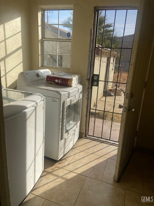 laundry area with light tile patterned floors, separate washer and dryer, and plenty of natural light