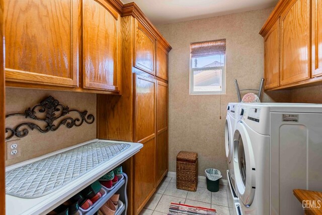 clothes washing area with light tile patterned floors, separate washer and dryer, cabinet space, and baseboards