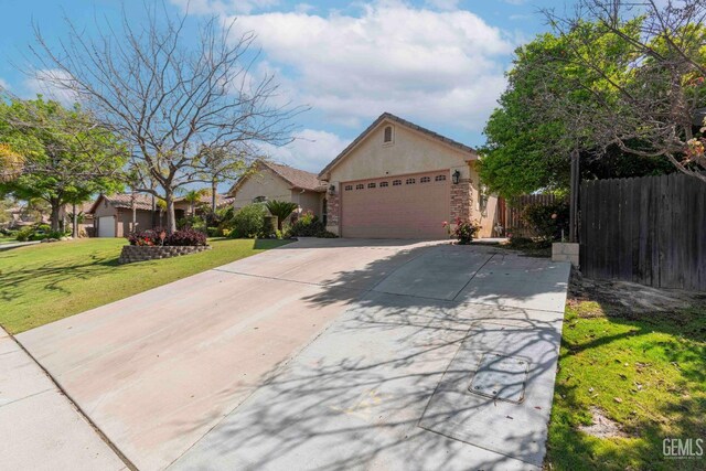 single story home with stucco siding, fence, a front lawn, concrete driveway, and an attached garage