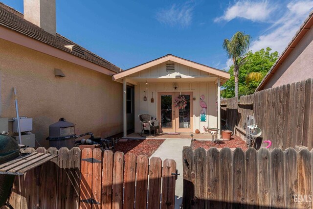 doorway to property featuring a chimney, stucco siding, a gate, fence, and french doors