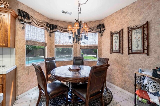 dining area featuring a chandelier, visible vents, light tile patterned flooring, and baseboards