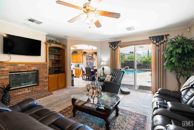 living area with crown molding, arched walkways, visible vents, and ceiling fan