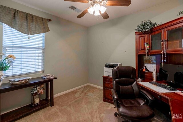 office area featuring a ceiling fan, visible vents, light carpet, and baseboards