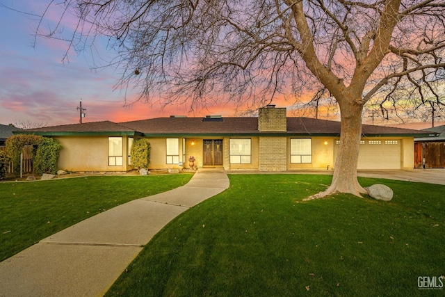 ranch-style home featuring a garage and a yard