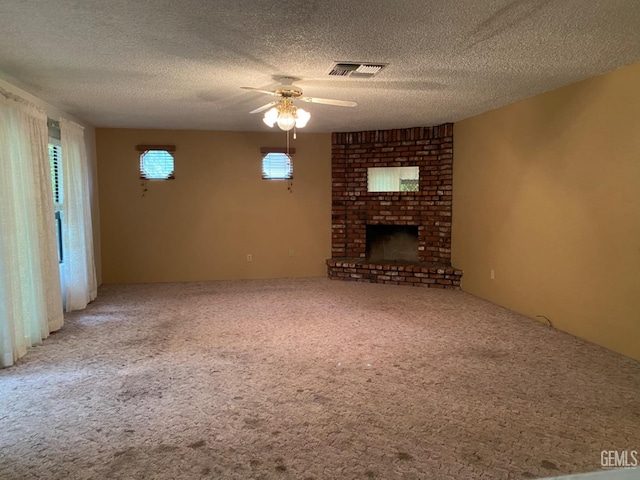 unfurnished living room with a textured ceiling, ceiling fan, a fireplace, and carpet