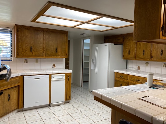 kitchen with tile countertops, white appliances, and tasteful backsplash