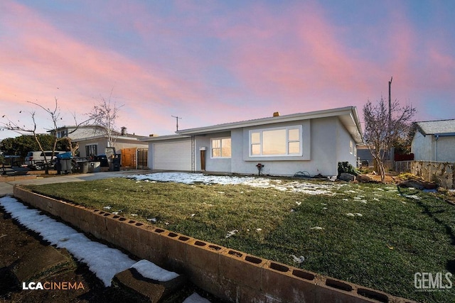 ranch-style home featuring a garage and a yard