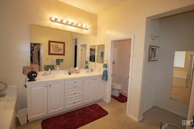 bathroom with vanity, toilet, and a tub to relax in