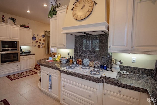 kitchen featuring white gas cooktop, oven, white cabinets, and premium range hood