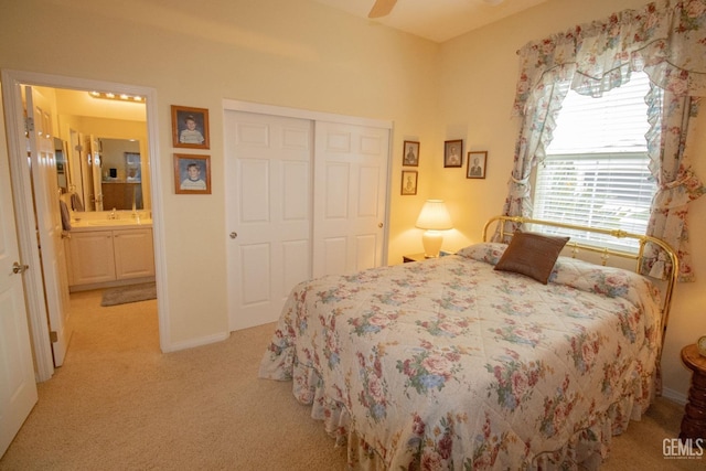 carpeted bedroom with ceiling fan, ensuite bath, sink, and a closet