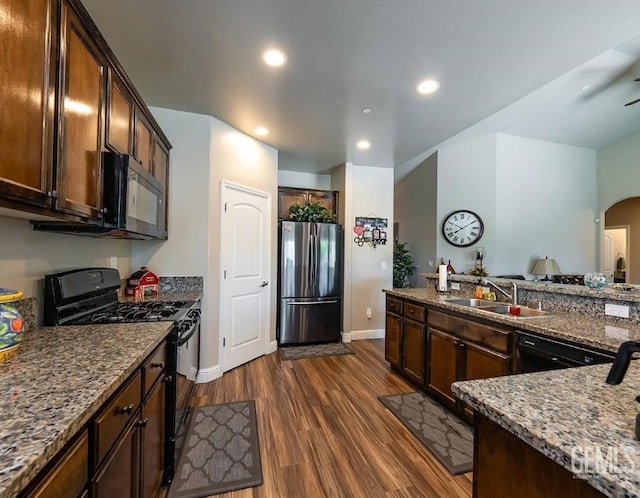 1756 Bautista Ave, Wasco, CA 93280 - kitchen with black appliances, dark wood-style flooring, arched walkways, recessed lighting, and dark brown cabinets