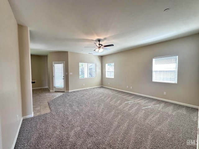carpeted empty room with ceiling fan and baseboards